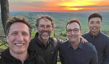 Four men posing during sunset with a scenic landscape backdrop.