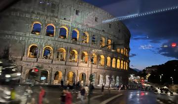 The Colosseum illuminated at night with people around.
