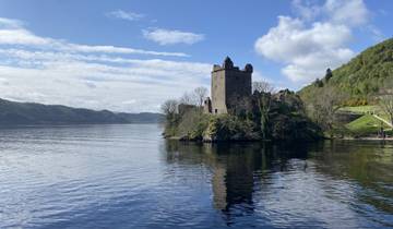 Historic castle overlooking a serene lake surrounded by hills.