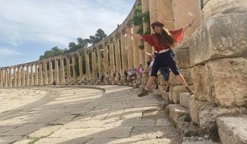 Person jumping in the foreground of an ancient colonnade.
