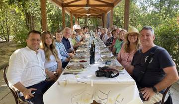 Large group of people dining at a long table outdoors.