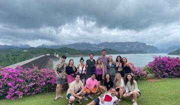 Group of people posing in front of a scenic landscape with water and mountains.