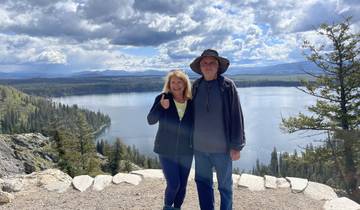 Couple posing with a stunning view of a lake and mountains.