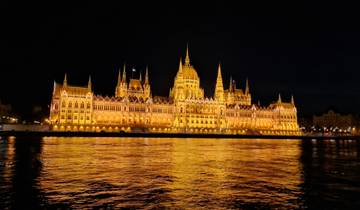 Illuminated parliament building with reflection in water.