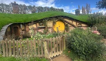 Hobbit-style house with a yellow door in a garden.