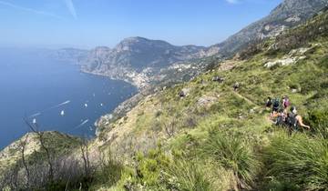 Hikers on a trail overlooking a scenic coastal landscape.