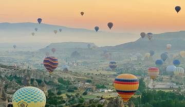 Hot air balloons rising over the landscape at dawn.