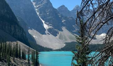Vibrant turquoise lake with steep mountain peaks.