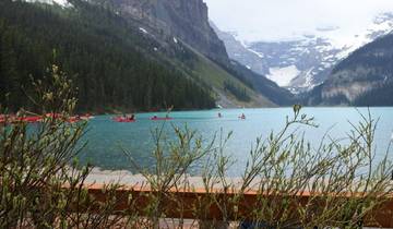 Canoes on a turquoise lake with mountains in the background.