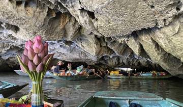 People in small boats floating in a cave with stalactites.