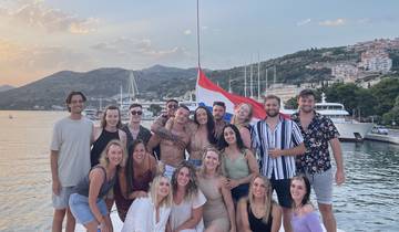 A group of people smiling and posing in a yacht harbor during sunset.