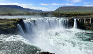 A wide waterfall under a clear blue sky.