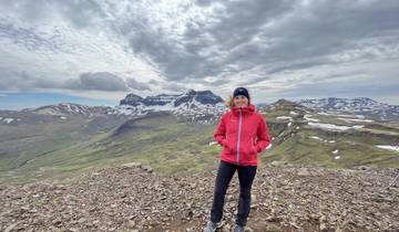 Person posing on a rocky mountain with snow patches.