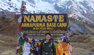 Person posing at Annapurna Base Camp sign.