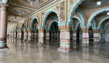 Ornate hall with rows of intricately decorated arches and columns reflecting on a shiny floor.