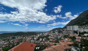 Panoramic view of a city with mountains and a partly cloudy sky.