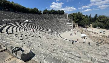 Ancient Greek amphitheater with scattered tourists exploring.