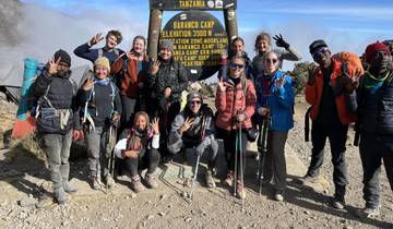 Group of hikers posing with trekking poles at Barranco Camp sign.