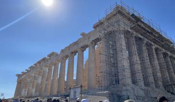 View of the Parthenon under restoration work, against a bright blue sky.