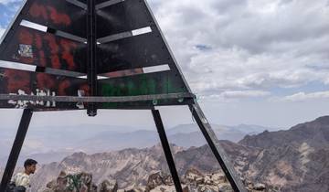 Summit marker on top of a mountain with a view of ranges.