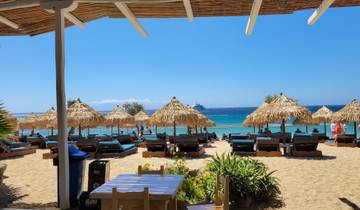 Beach scene with straw umbrellas and loungers overlooking the sea.