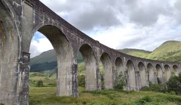 The Glenfinnan Viaduct in Scotland, surrounded by green hills.