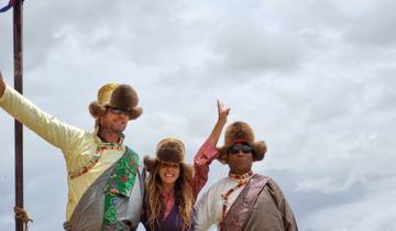 Three people wearing traditional attire with fur hats standing outdoors.