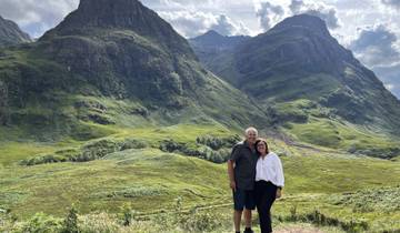 Couple standing in front of rolling hills and mountains.