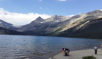 Mountainous landscape with a lake shoreline and people.