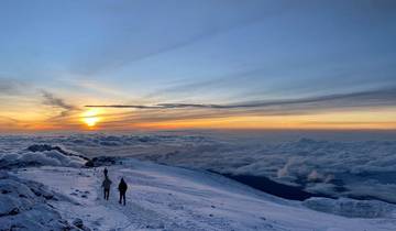 Snowy mountain landscape with two people walking at sunrise.