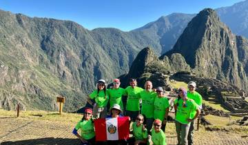 A group posing with the Peruvian flag at Machu Picchu.