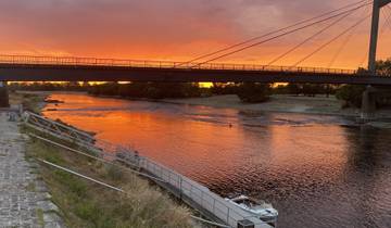 Sunset view of a bridge over a calm river.