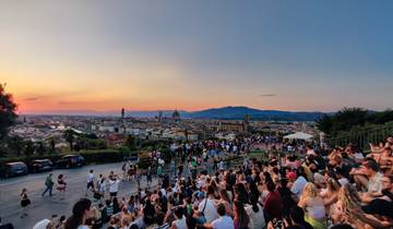Crowd at a viewpoint overlooking a city at sunset.