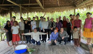 Group of people posing at a local village with thatched roof building