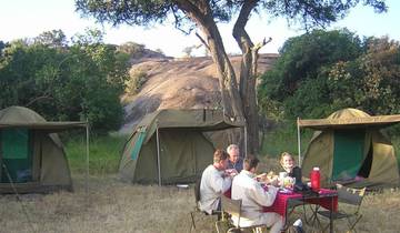 People dining outside with tents in the background