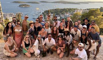 Large group of people with coastal town and sea in the background.