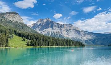 Canoers on a turquoise lake surrounded by mountains.