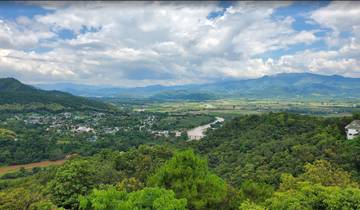 A panoramic view of a valley with a river and mountains in the background.