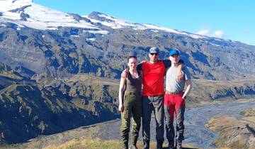 Three hikers standing together in front of a mountainous backdrop.