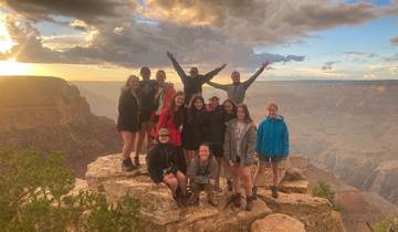 Group of people posing on a cliff with a canyon view.
