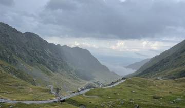 Mountain pass with a winding road and cloudy sky.