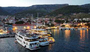 Harbor at dusk with yachts and illuminated buildings.