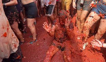Group of people covered in smashed tomatoes at a festival.