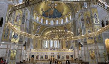 Interior of a grand church with gold mosaics and chandeliers.