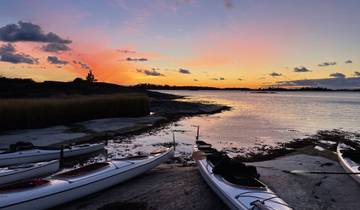 Kayaks by a serene waterfront at sunset.