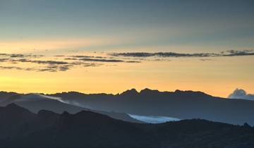 Mountain silhouette against a colorful sky at sunrise.