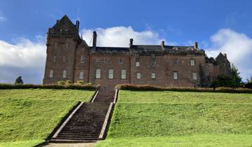 Large castle on a hill with stone stairs leading up.