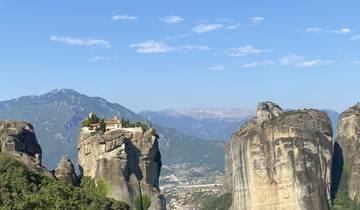 Cliffside monastery complex amidst rugged mountains.