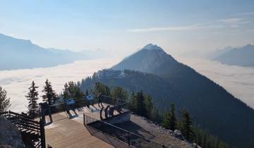 Viewing platform with tourists overlooking mountains and clouds.