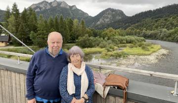 Couple posing on a bridge with mountain landscape and river.